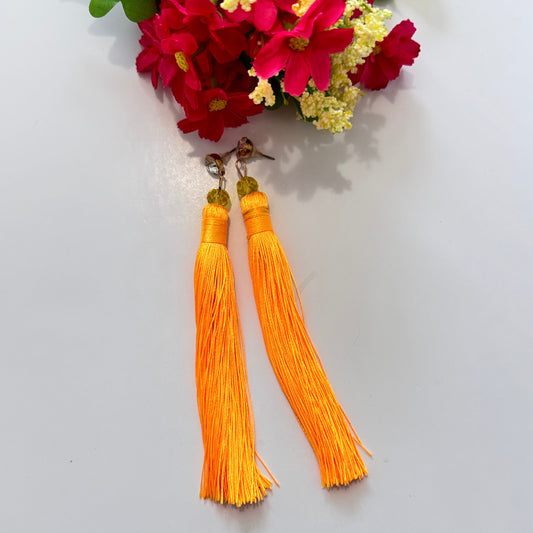 Turn heads with these stunning tassel earrings, designed to infuse your look with vibrant energy and effortless elegance. Featuring a mesmerizing shade of bold, sunshine-orange thread, these long, silky tassels sway gracefully with every movement, creating a captivating effect. Accentuated by delicate golden-hued beads and a sleek metallic stud, these earrings are the perfect statement piece for anyone who loves bold, eye-catching accessories. 
