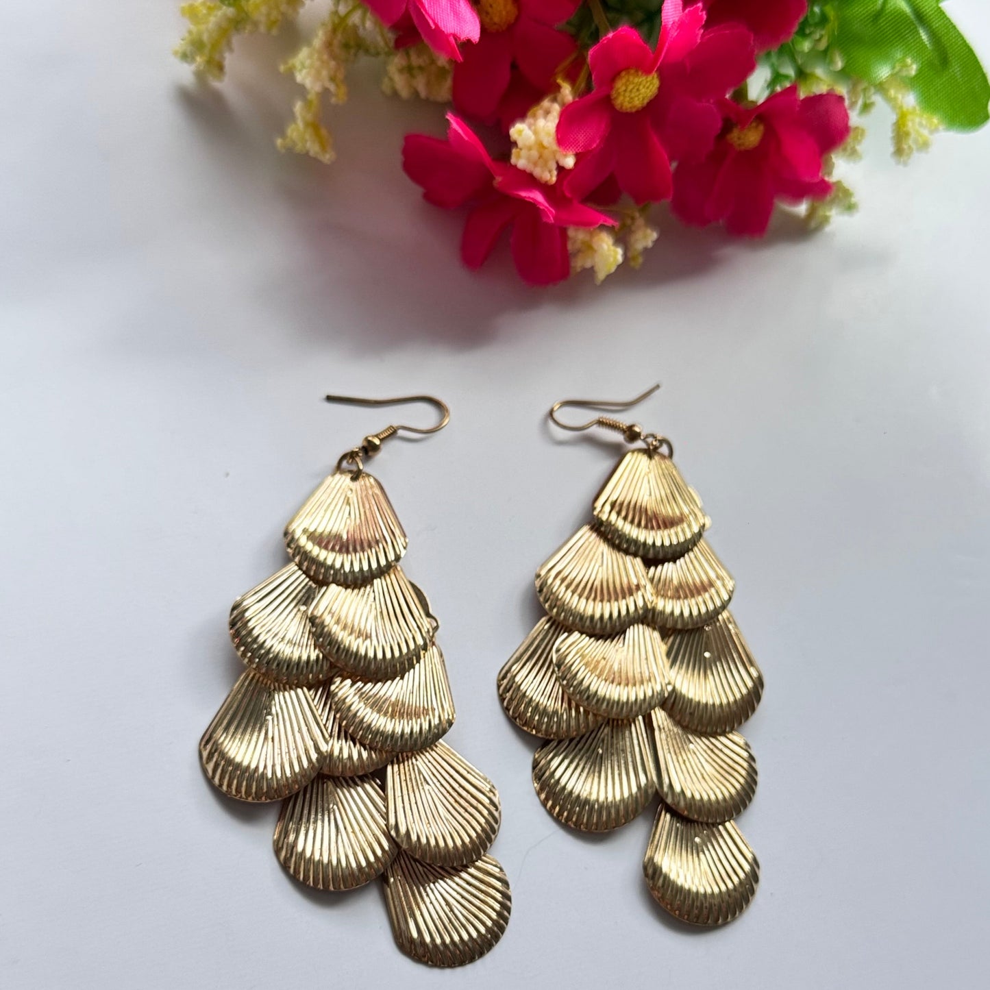 Introducing our Golden Cascade Shell Earrings, a stunning statement piece inspired by the elegance of ocean waves and timeless luxury. Designed with multiple layers of delicately textured, fan-shaped golden charms, these earrings create a mesmerizing waterfall effect that catches the light with every movement.