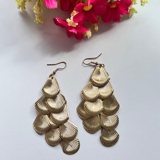Introducing our Golden Cascade Shell Earrings, a stunning statement piece inspired by the elegance of ocean waves and timeless luxury. Designed with multiple layers of delicately textured, fan-shaped golden charms, these earrings create a mesmerizing waterfall effect that catches the light with every movement.