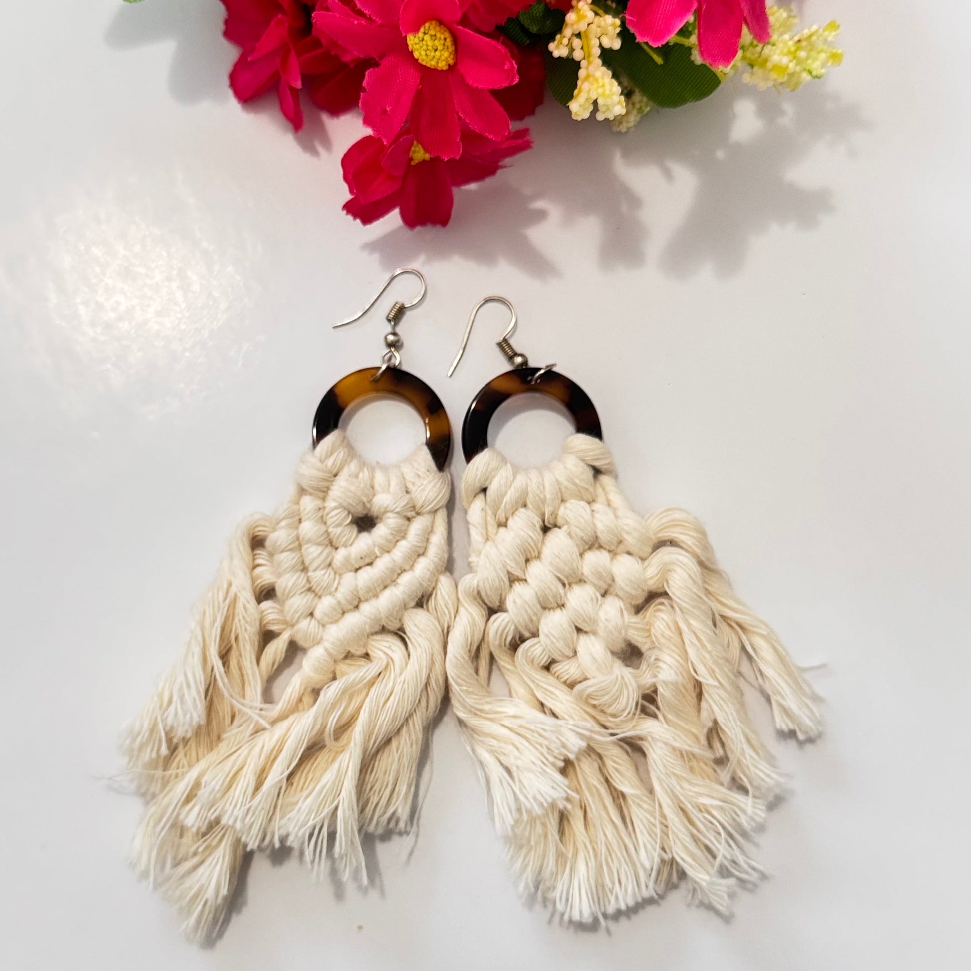 These stunning earrings showcase intricate macramé knotting in soft, natural cream and blush pink hues, complemented by a chic tortoiseshell ring that adds a touch of sophistication. The lightweight, flowy tassels create movement and charm, making these earrings the ultimate statement accessory for any outfit.