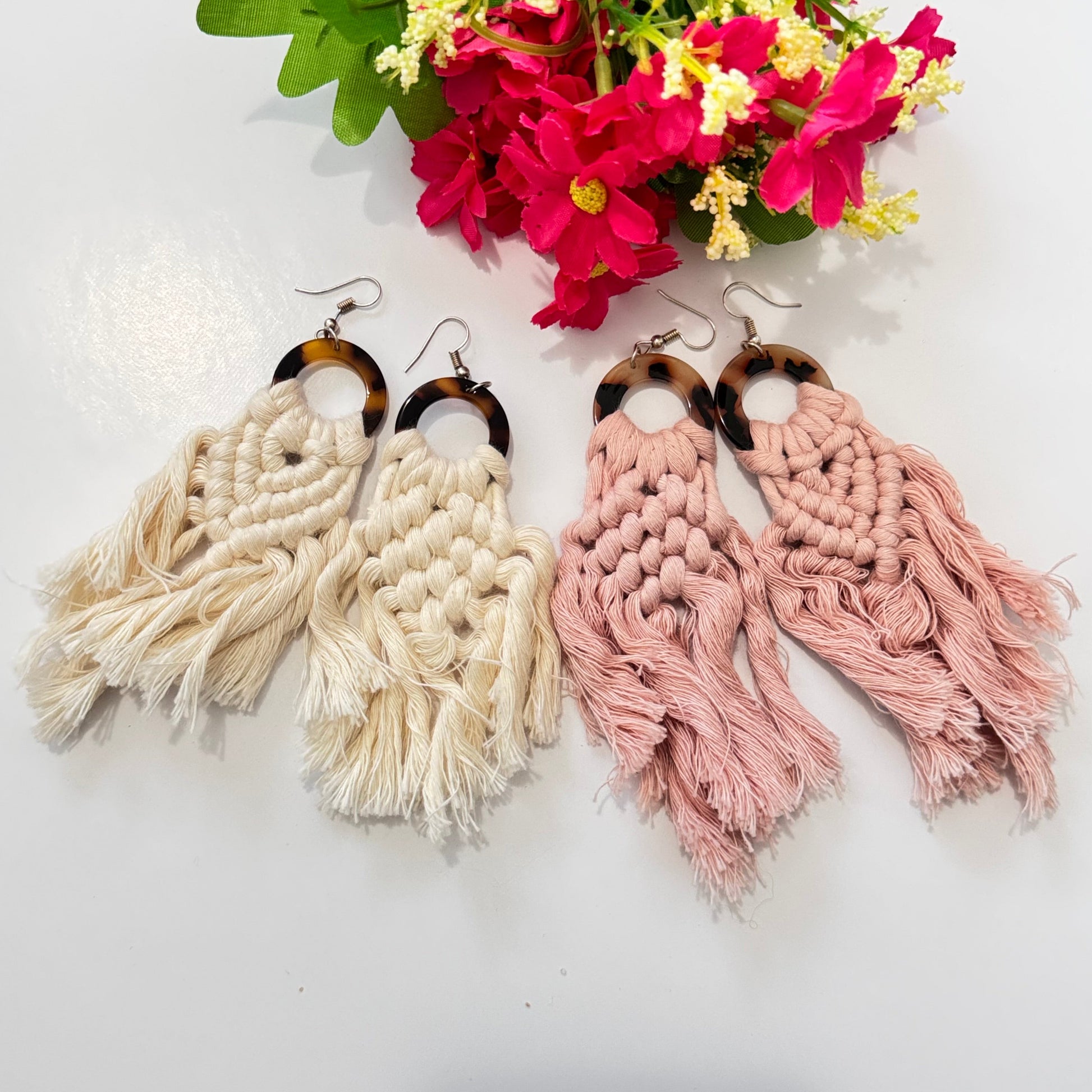 These stunning earrings showcase intricate macramé knotting in soft, natural cream and blush pink hues, complemented by a chic tortoiseshell ring that adds a touch of sophistication. The lightweight, flowy tassels create movement and charm, making these earrings the ultimate statement accessory for any outfit.