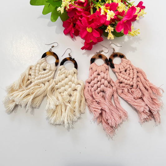 These stunning earrings showcase intricate macramé knotting in soft, natural cream and blush pink hues, complemented by a chic tortoiseshell ring that adds a touch of sophistication. The lightweight, flowy tassels create movement and charm, making these earrings the ultimate statement accessory for any outfit.