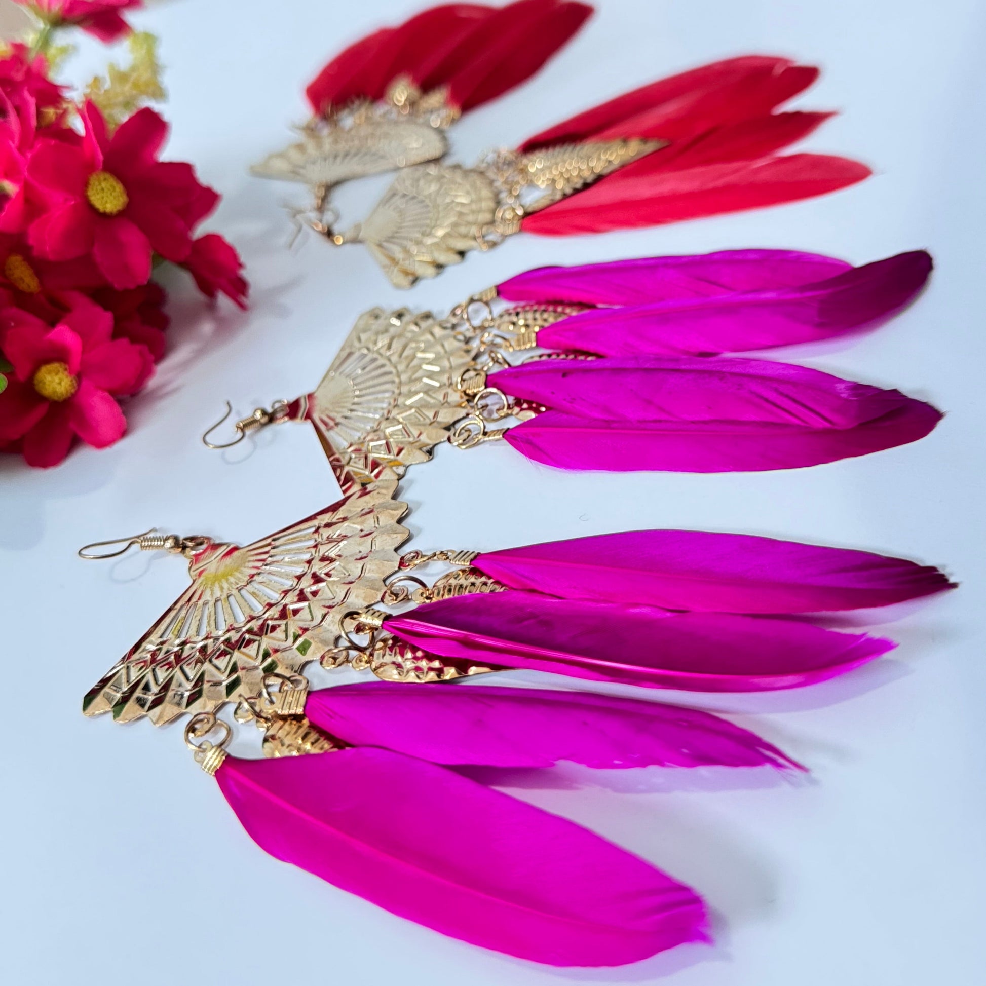  These breathtaking fan-shaped gold earrings feature intricate detailing, exuding a luxurious charm that captivates at first glance. Adorned with vibrant feather accents in striking red and fuchsia hues, they add a dramatic flair to any outfit, making them perfect for fashion-forward people who love to stand out. 