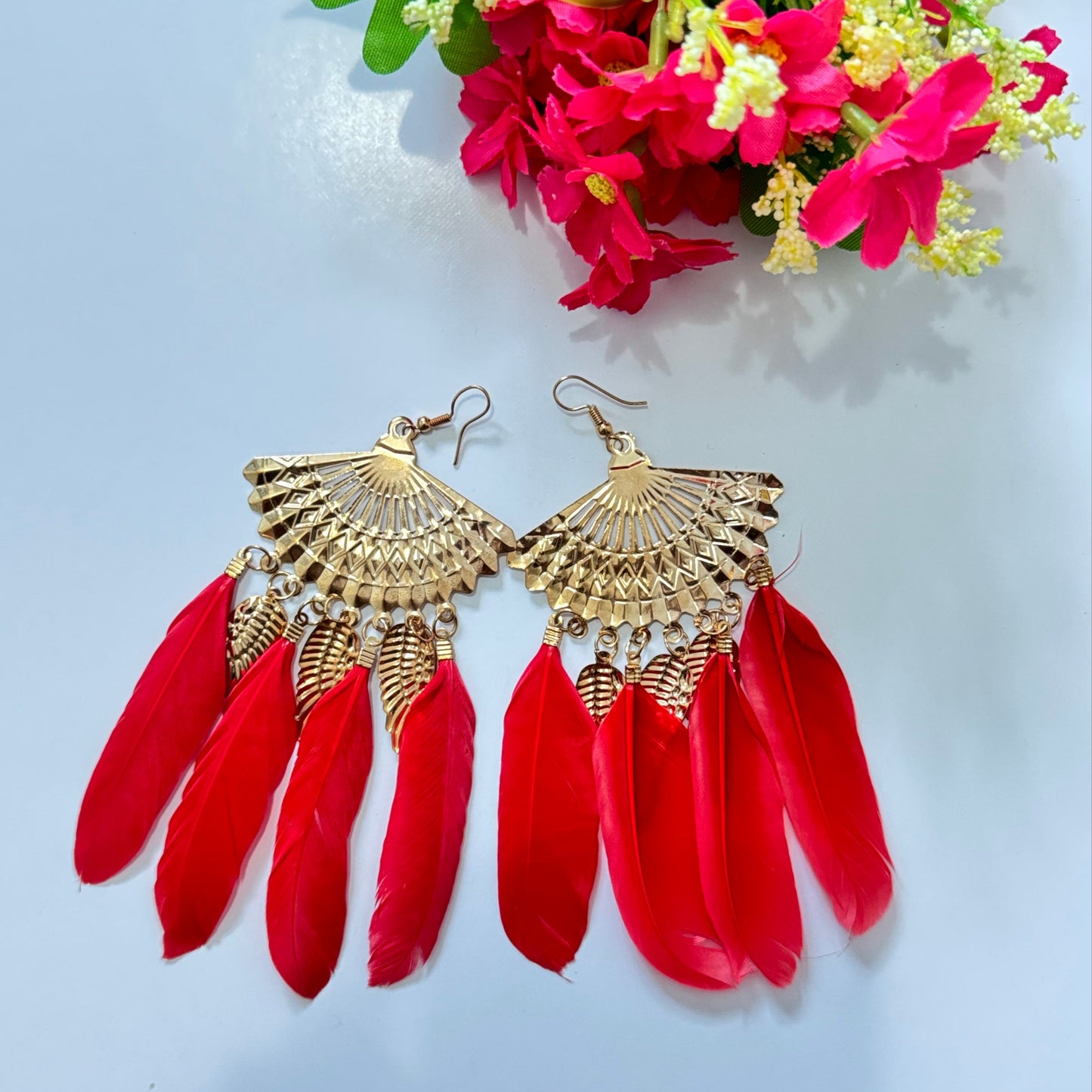  These breathtaking fan-shaped gold earrings feature intricate detailing, exuding a luxurious charm that captivates at first glance. Adorned with vibrant feather accents in striking red and fuchsia hues, they add a dramatic flair to any outfit, making them perfect for fashion-forward people who love to stand out. 