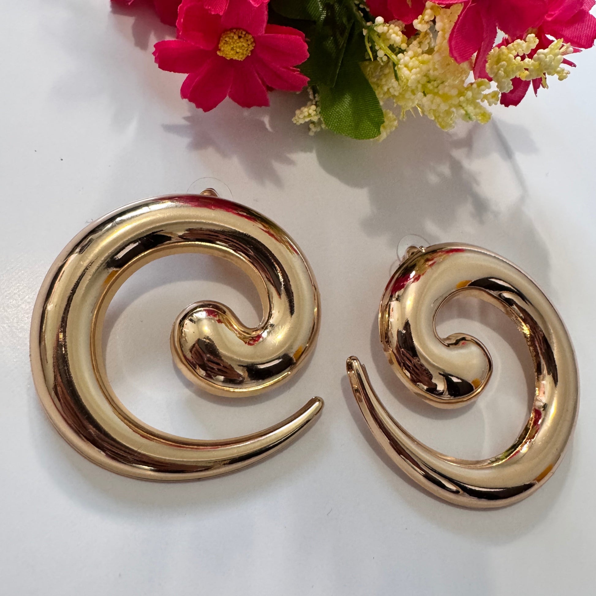 Unleash your inner goddess with these stunning Golden Swirl Statement Earrings, designed to make a lasting impression. Featuring a sleek, spiral silhouette with a high-shine gold finish, these earrings blend modern sophistication with artistic flair. 