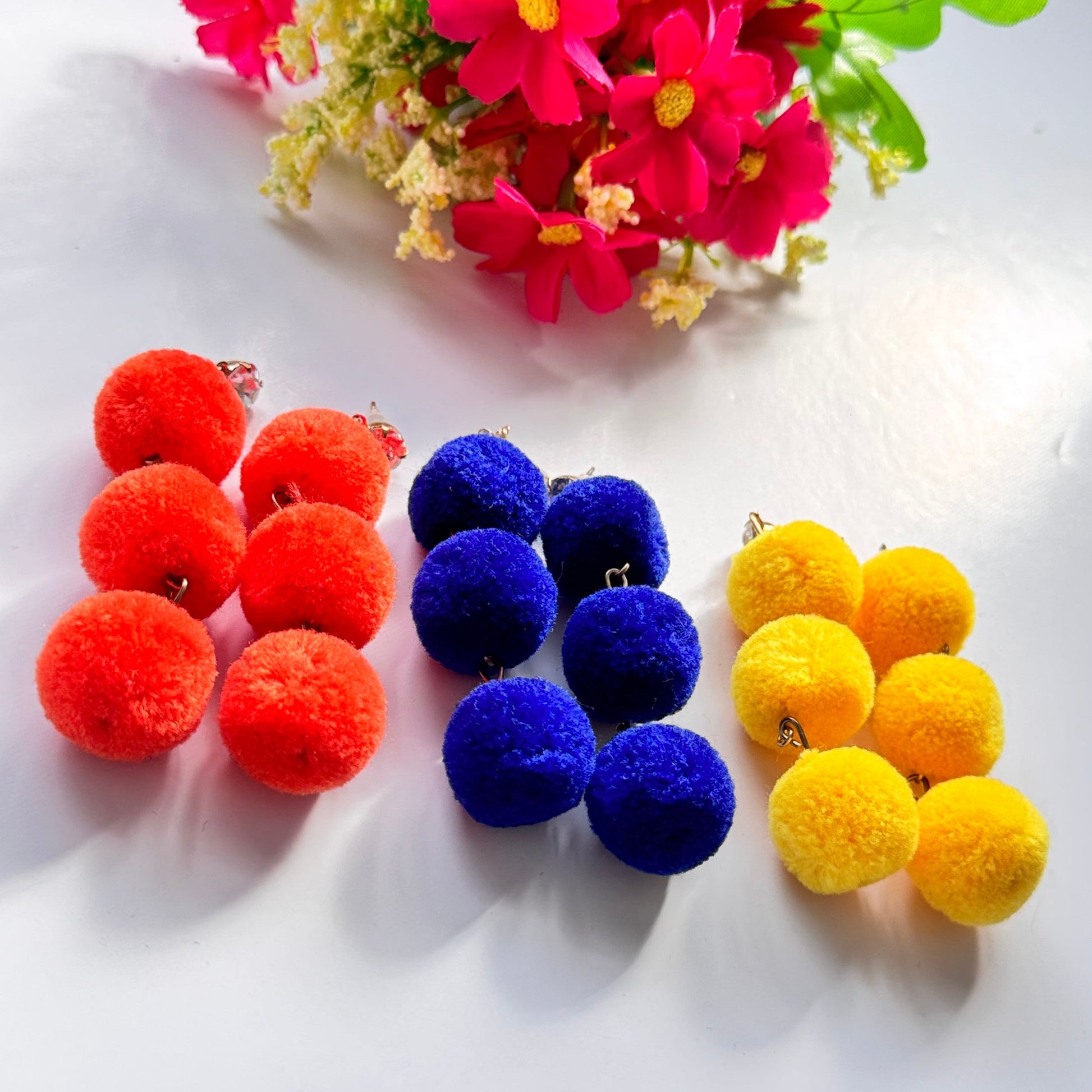 Designed to make a bold statement, these playful yet chic earrings feature three fluffy, lightweight pom-poms stacked elegantly for a dynamic, eye-catching effect. Available in fiery orange, deep royal blue, and radiant sunshine yellow, these earrings bring a fun and energetic touch to any outfit.