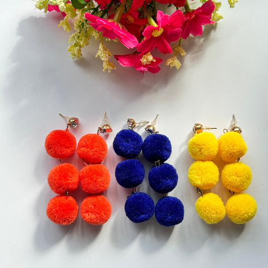 Designed to make a bold statement, these playful yet chic earrings feature three fluffy, lightweight pom-poms stacked elegantly for a dynamic, eye-catching effect. Available in fiery orange, deep royal blue, and radiant sunshine yellow, these earrings bring a fun and energetic touch to any outfit.