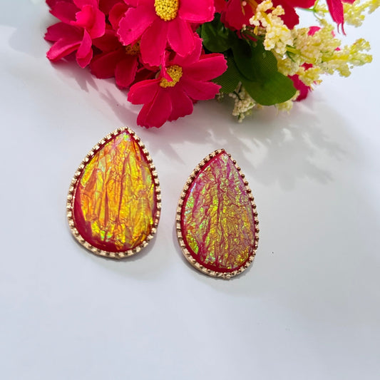 These teardrop-shaped stunners feature a mesmerizing iridescent design that shimmers with golden-orange and crimson undertones, encased in a delicate, sparkling border for a touch of elegance. The unique crinkled texture creates a captivating play of light, ensuring that these earrings stand out in any setting. 