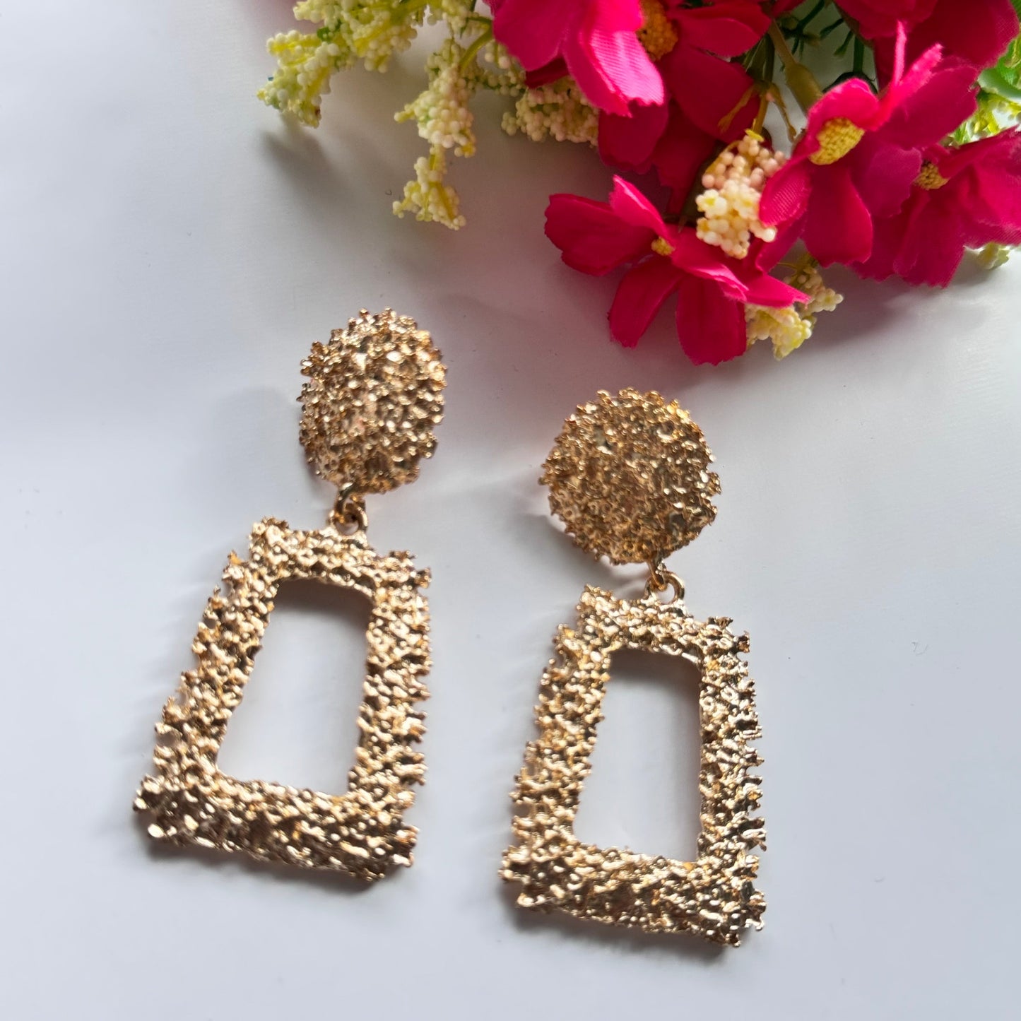 Elevate your style with these stunning gold-textured statement earrings, designed to make you shine effortlessly. Featuring an intricate crushed-metal design, these bold geometric dangle earrings add an instant touch of glamour to any outfit. The elegant open rectangle drop paired with a textured stud top creates a luxurious, modern appeal that catches the light beautifully with every movement.