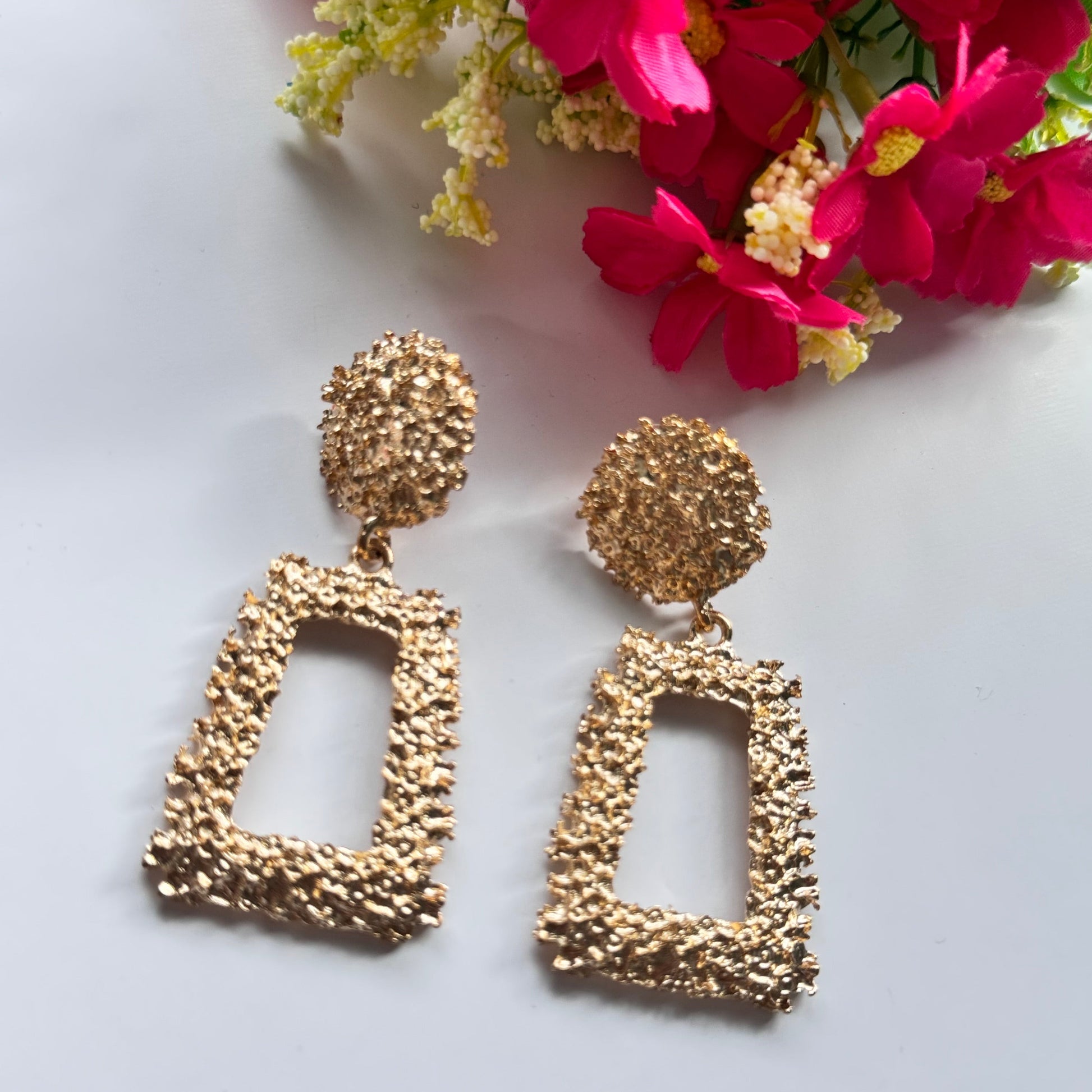 Elevate your style with these stunning gold-textured statement earrings, designed to make you shine effortlessly. Featuring an intricate crushed-metal design, these bold geometric dangle earrings add an instant touch of glamour to any outfit. The elegant open rectangle drop paired with a textured stud top creates a luxurious, modern appeal that catches the light beautifully with every movement.