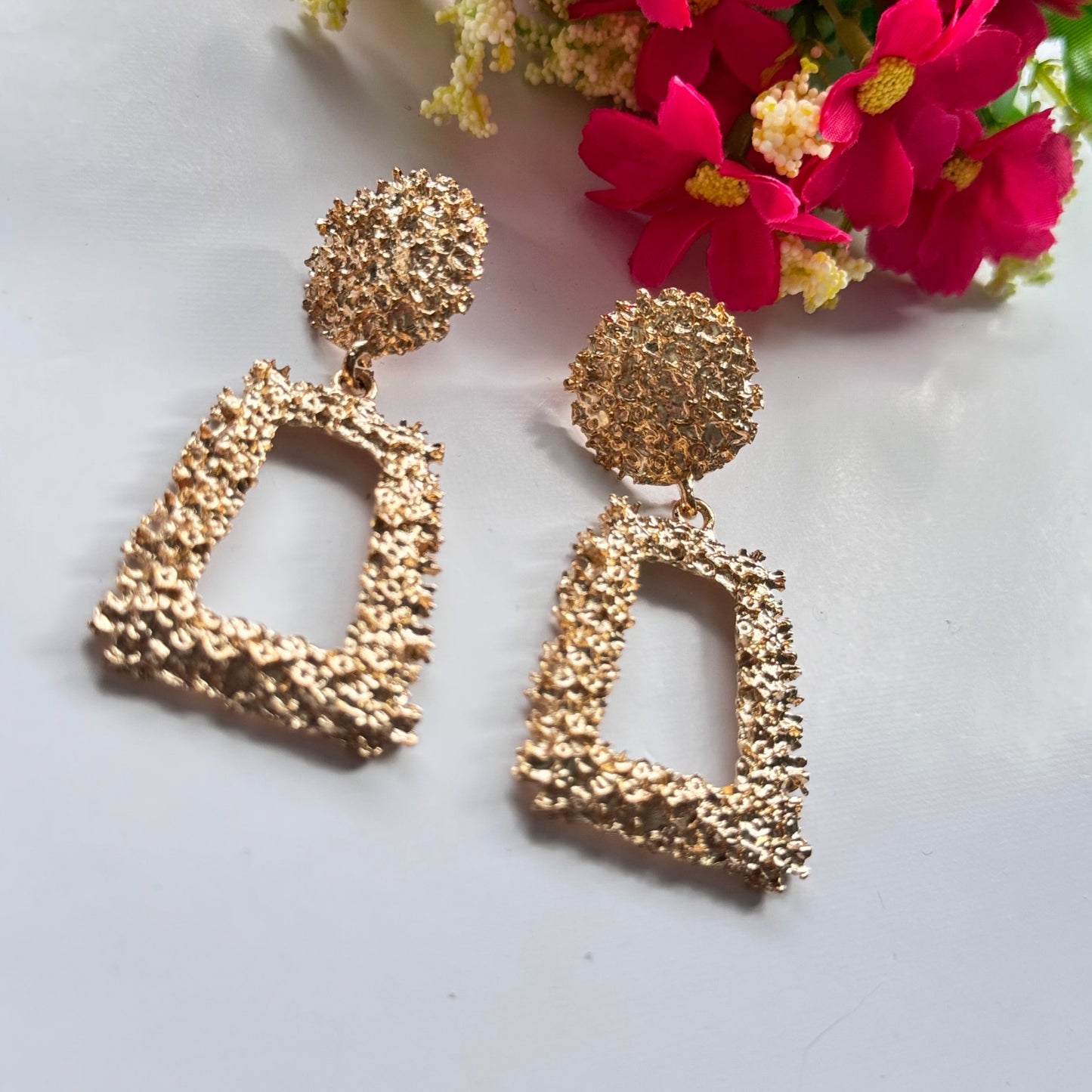 Elevate your style with these stunning gold-textured statement earrings, designed to make you shine effortlessly. Featuring an intricate crushed-metal design, these bold geometric dangle earrings add an instant touch of glamour to any outfit. The elegant open rectangle drop paired with a textured stud top creates a luxurious, modern appeal that catches the light beautifully with every movement.