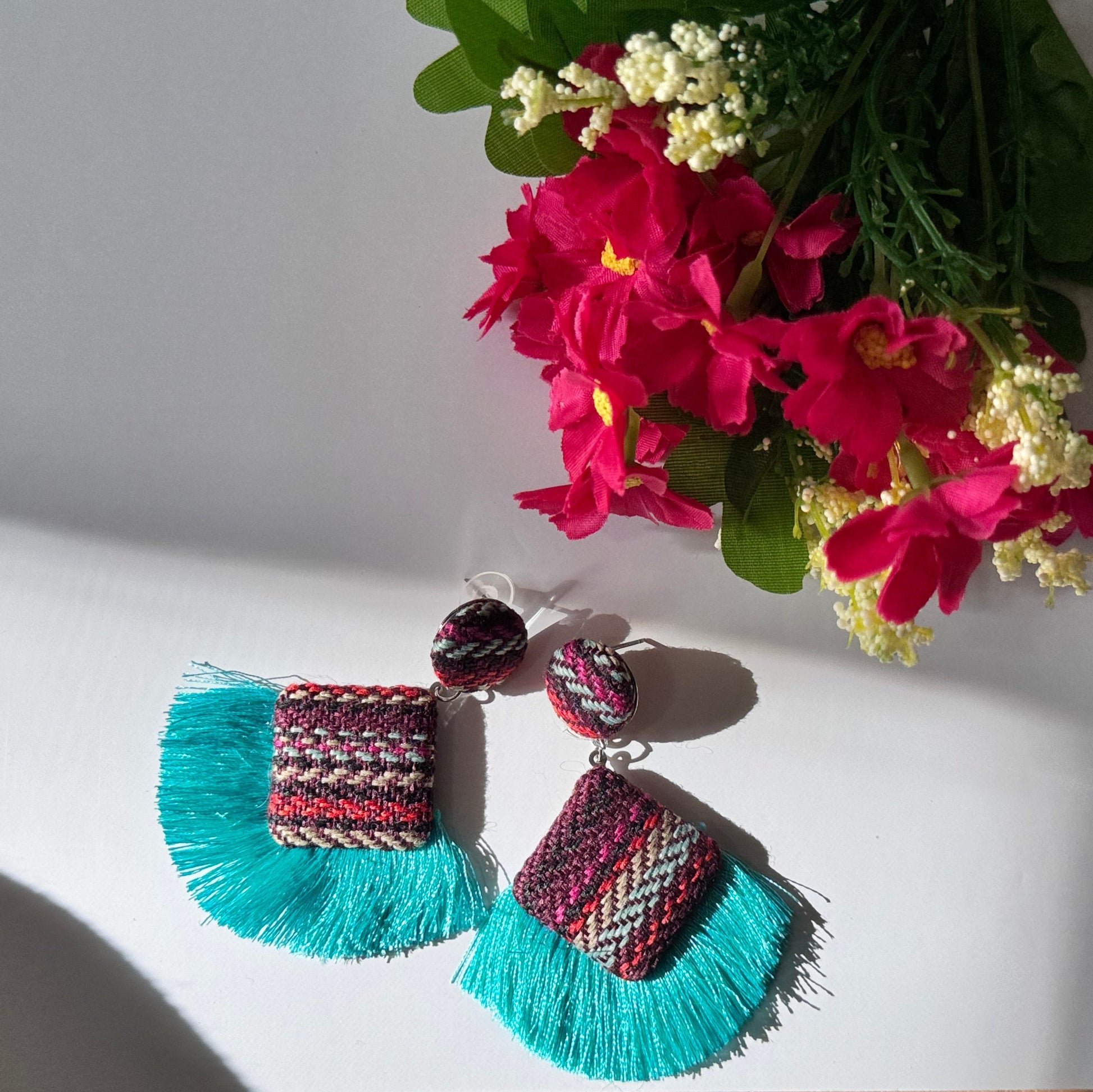 These stunning, artisan-crafted statement pieces feature a unique woven textile design, accented with luxurious silky tassels in bold turquoise and royal blue hues. Designed for trendsetters, these earrings blend&nbsp;bohemian elegance with contemporary flair, making them the perfect accessory for festivals, beach vacations, or casual chic outfits. Lightweight yet bold, they are a must-have for fashion lovers who dare to stand out.
