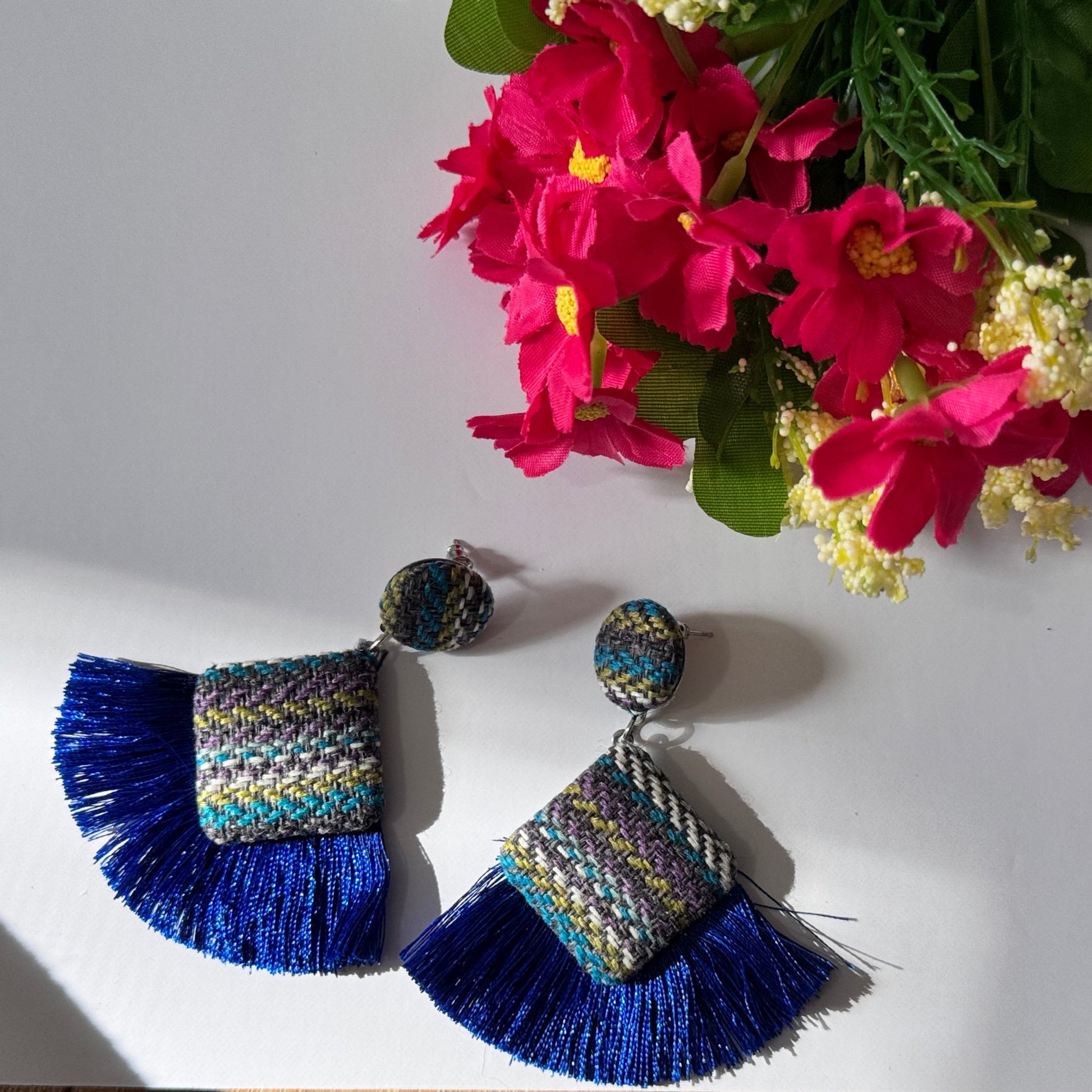 These stunning, artisan-crafted statement pieces feature a unique woven textile design, accented with luxurious silky tassels in bold turquoise and royal blue hues. Designed for trendsetters, these earrings blend&nbsp;bohemian elegance with contemporary flair, making them the perfect accessory for festivals, beach vacations, or casual chic outfits. Lightweight yet bold, they are a must-have for fashion lovers who dare to stand out.