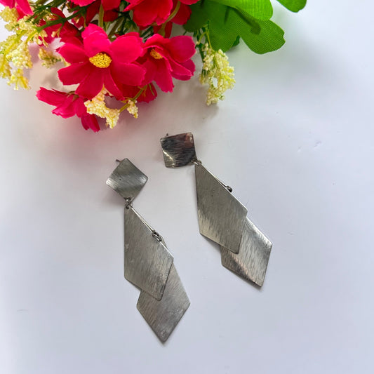 Make a sleek and sophisticated statement with these stunning silver-tone geometric drop earrings, designed to add a modern edge to any outfit. Featuring a cascading arrangement of brushed metal diamond-shaped panels, these earrings create an effortlessly chic and dynamic look. 