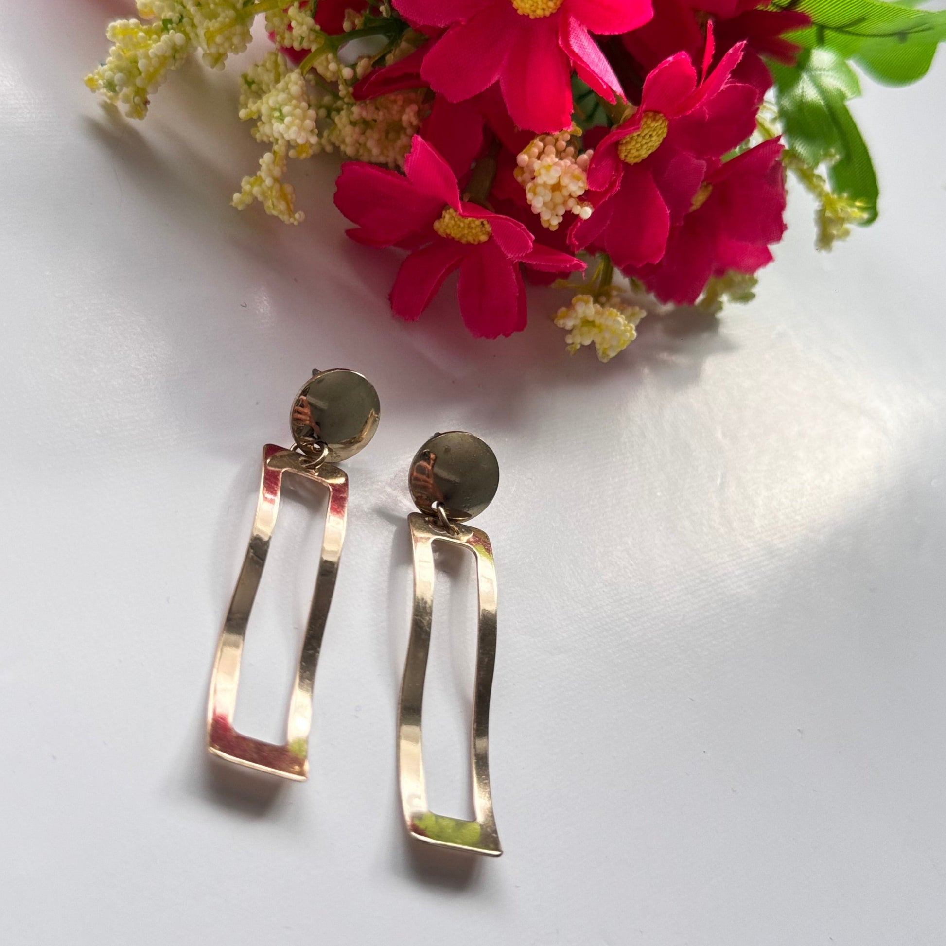 Elevate your style with these stunning, gold-tone dangle earrings designed to make a statement. Featuring a unique geometric open-rectangle silhouette, these lightweight earrings exude elegance with a modern, minimalist edge. The sleek, hammered finish adds a touch of artisanal charm, reflecting light beautifully with every movement. 