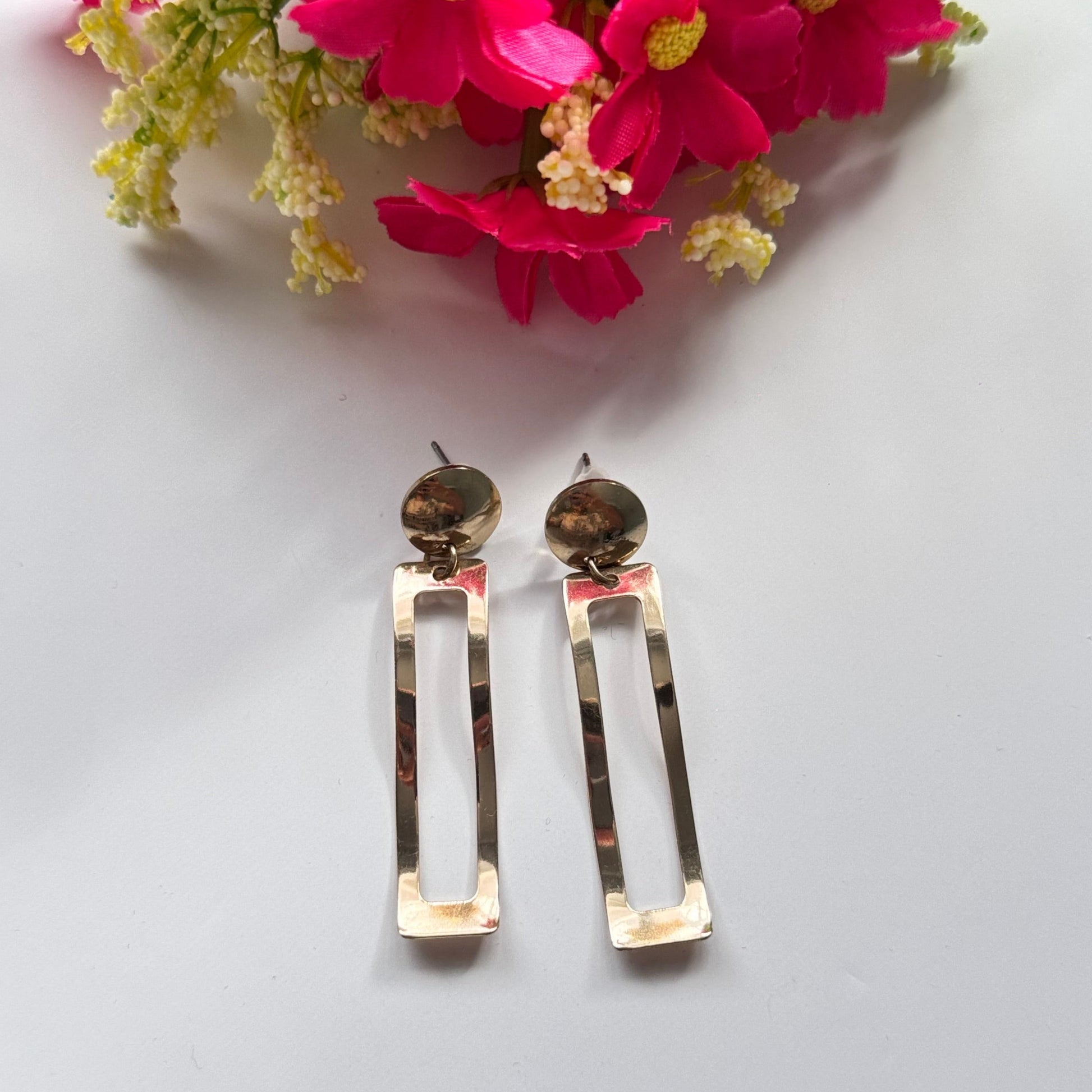 Elevate your style with these stunning, gold-tone dangle earrings designed to make a statement. Featuring a unique geometric open-rectangle silhouette, these lightweight earrings exude elegance with a modern, minimalist edge. The sleek, hammered finish adds a touch of artisanal charm, reflecting light beautifully with every movement. 