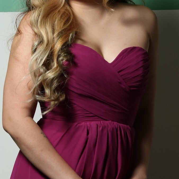 This elegant strapless gown features a beautifully ruched bodice and a flowing A-line skirt, creating a timeless and flattering silhouette. The rich magenta color adds a bold and sophisticated touch, perfect for formal events, bridesmaids, or special occasions. Crafted from lightweight fabric, it offers both comfort and style for an effortlessly graceful look.