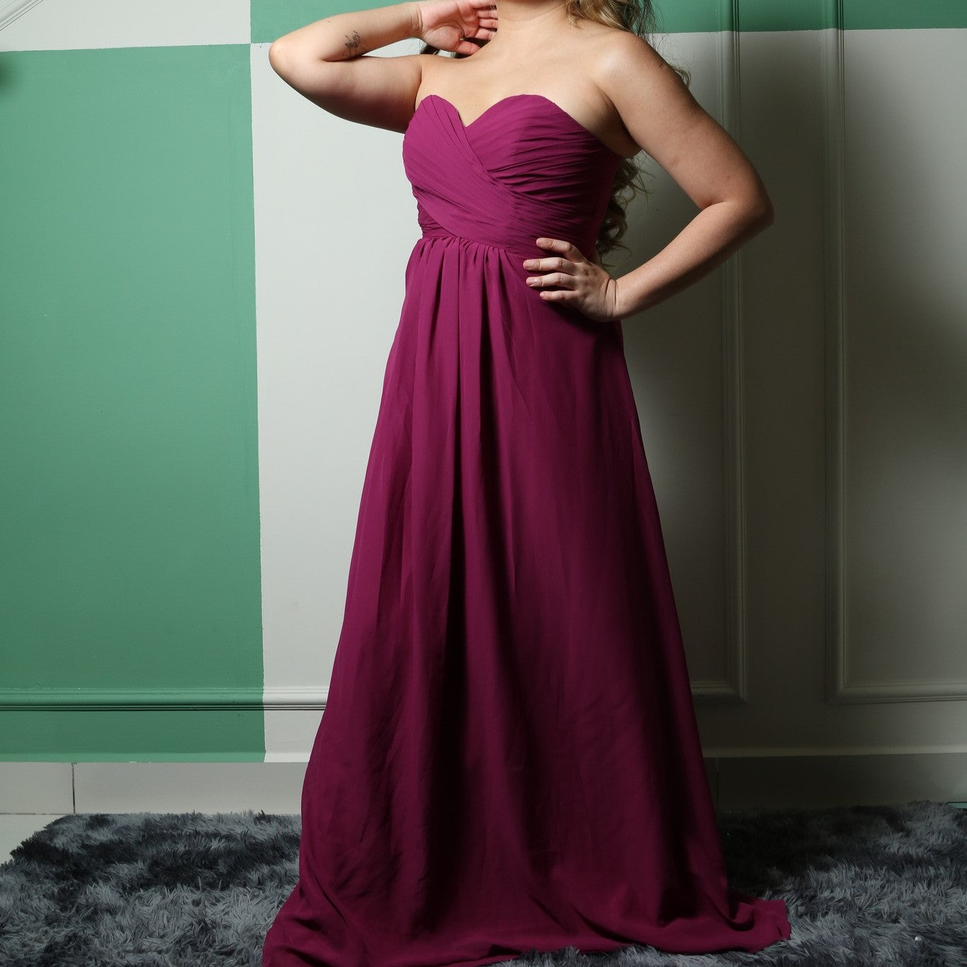 This elegant strapless gown features a beautifully ruched bodice and a flowing A-line skirt, creating a timeless and flattering silhouette. The rich magenta color adds a bold and sophisticated touch, perfect for formal events, bridesmaids, or special occasions. Crafted from lightweight fabric, it offers both comfort and style for an effortlessly graceful look.