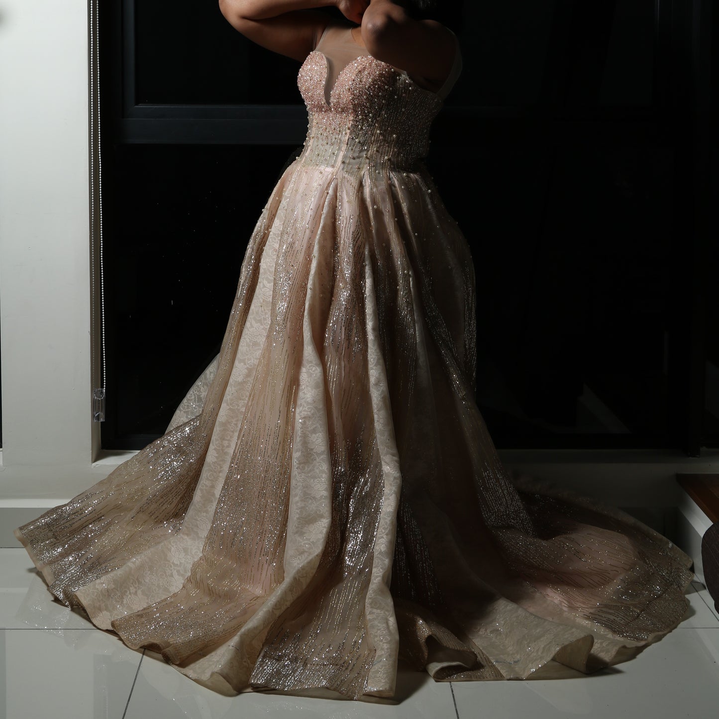 The dress in the image is an elegant, heavily embellished gown with a fitted bodice and a voluminous skirt. It features intricate beadwork and embroidery, giving it a luxurious and opulent look. The sheer illusion neckline adds a delicate touch, while the structured, corset-like bodice enhances the silhouette. The fabric appears to be thick and richly adorned, making the dress quite heavy. The overall design exudes a regal and glamorous feel, perfect for a formal event or gala.