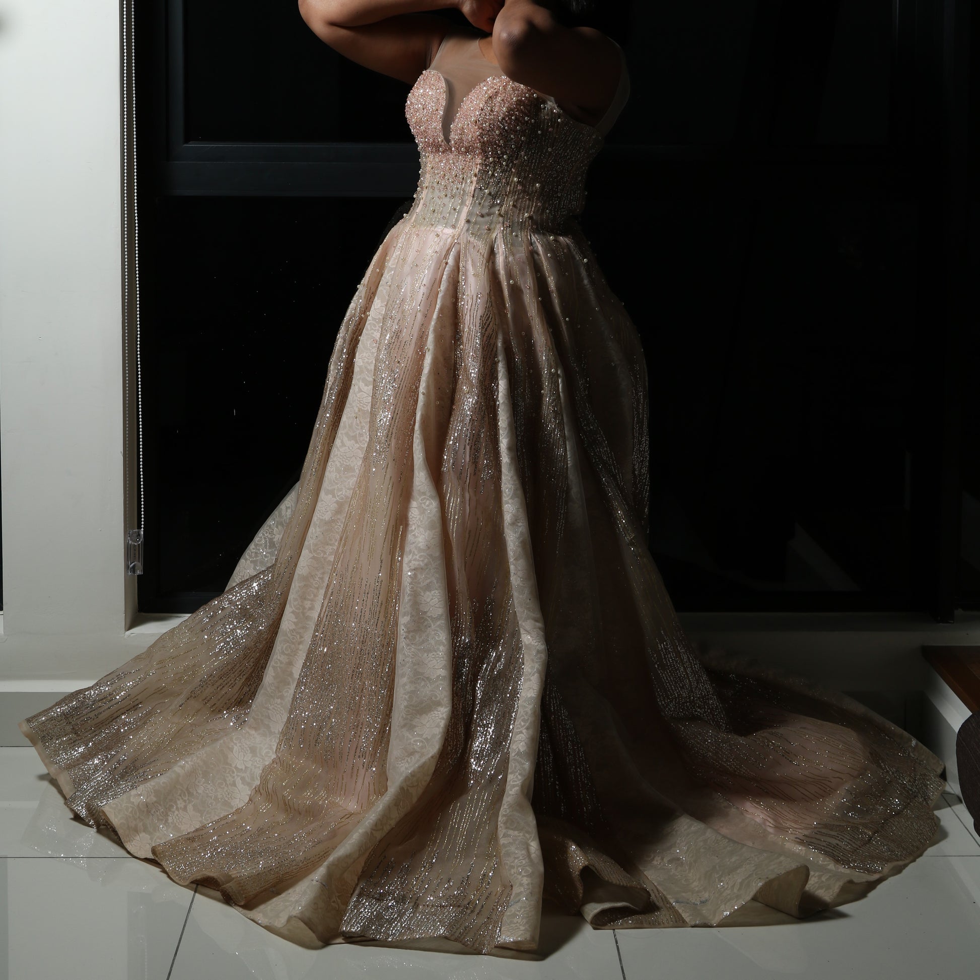 The dress in the image is an elegant, heavily embellished gown with a fitted bodice and a voluminous skirt. It features intricate beadwork and embroidery, giving it a luxurious and opulent look. The sheer illusion neckline adds a delicate touch, while the structured, corset-like bodice enhances the silhouette. The fabric appears to be thick and richly adorned, making the dress quite heavy. The overall design exudes a regal and glamorous feel, perfect for a formal event or gala.
