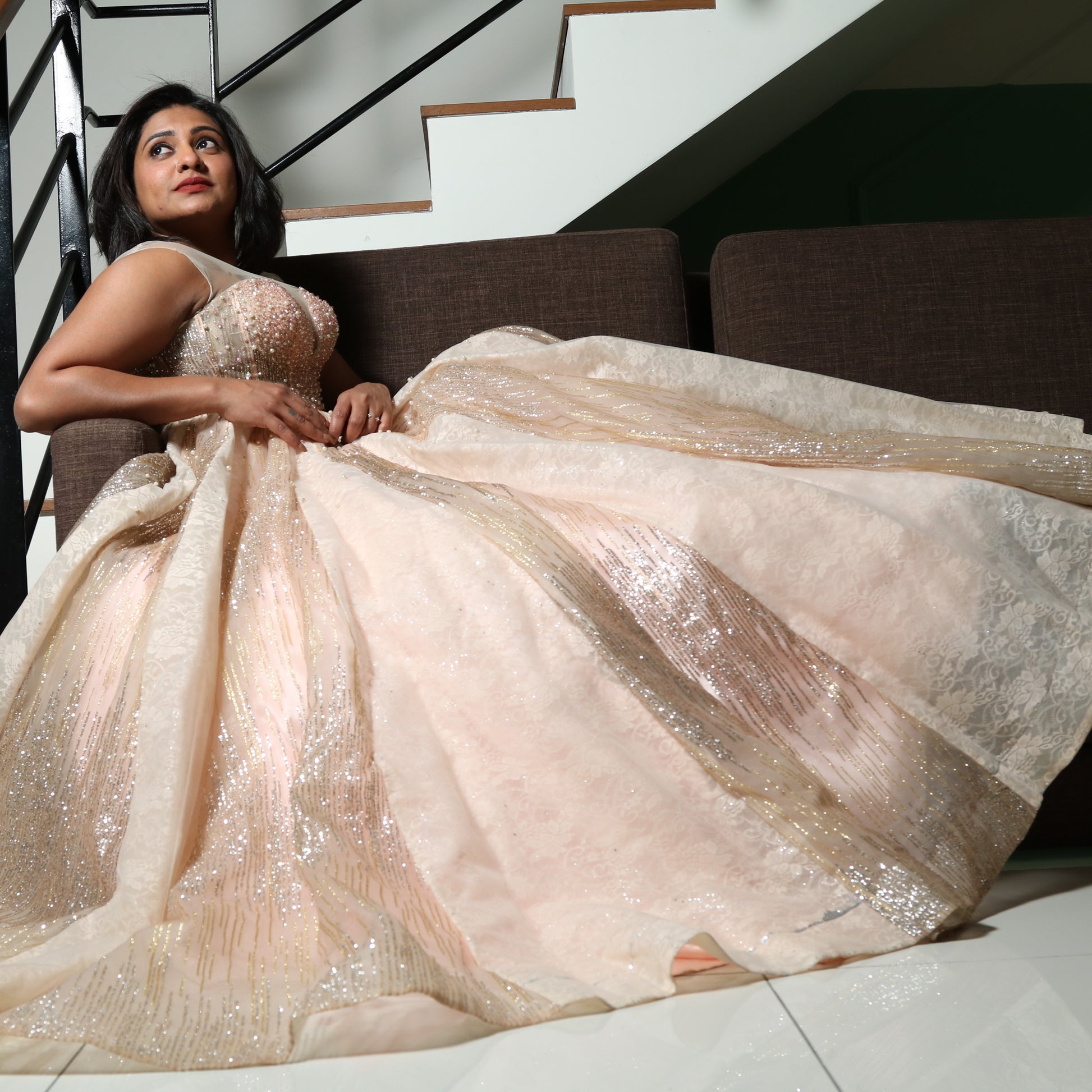 The dress in the image is an elegant, heavily embellished gown with a fitted bodice and a voluminous skirt. It features intricate beadwork and embroidery, giving it a luxurious and opulent look. The sheer illusion neckline adds a delicate touch, while the structured, corset-like bodice enhances the silhouette. The fabric appears to be thick and richly adorned, making the dress quite heavy. The overall design exudes a regal and glamorous feel, perfect for a formal event or gala.