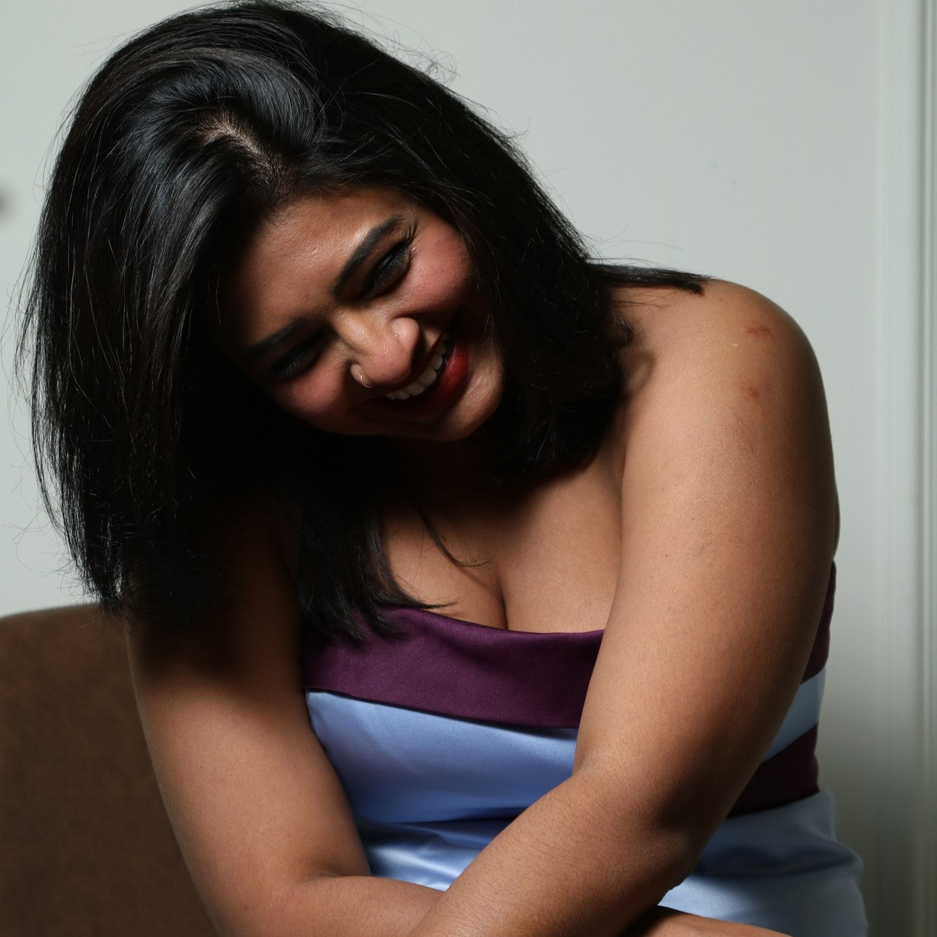 This elegant evening dress is perfect for someone with a curvy figure, as it beautifully accentuates natural shape with its structured, strapless bodice and flowing floor-length satin skirt. The light blue fabric is complemented by a deep purple band across the bust and waist, creating a flattering color-blocked effect that enhances the silhouette. The design exudes sophistication and grace, making it an excellent choice for formal occasions