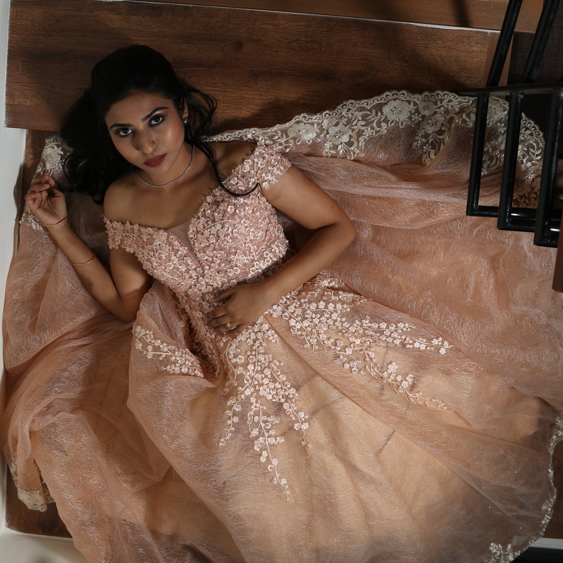 This exquisite gown exudes grace and sophistication with its intricate floral embroidery and delicate lace appliqués. The soft peach hue complements the voluminous layers of fabric, creating a regal and ethereal silhouette. The sheer detailing on the bodice adds a touch of elegance, while the heavy structure of the dress enhances its grandeur. Perfect for a gala, wedding, or any formal affair, this masterpiece is a true blend of luxury and artistry.