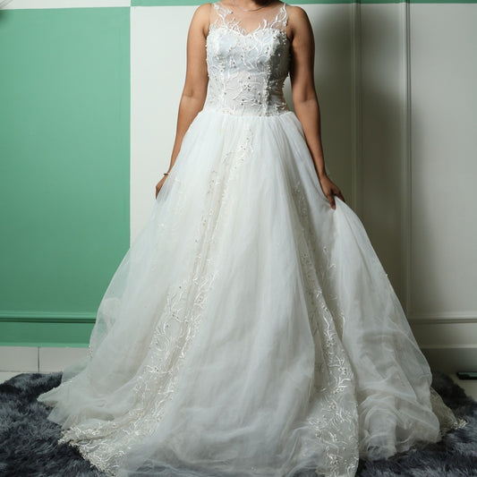 This wedding gown is a light and airy gown featuring a sheer illusion neckline and intricate floral embroidery on the bodice. The flowing tulle skirt is delicately adorned with subtle embellishments, adding an ethereal touch to its elegant silhouette.