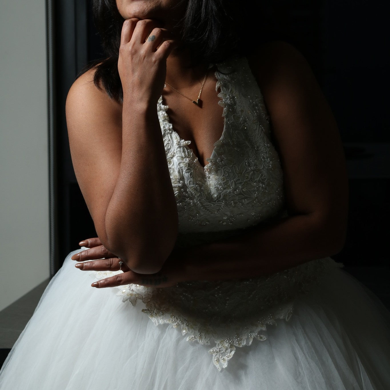 This dress is a stunning white gown with a voluminous tulle skirt, creating an ethereal and lightweight appearance. The bodice features intricate lace or beaded detailing with a flattering V-neckline and sleeveless design. The skirt is made of multiple layers of airy tulle, giving it a dreamy, floating effect. The overall look is elegant, romantic, and light, making it a perfect choice for a formal event such as a wedding or a gala.