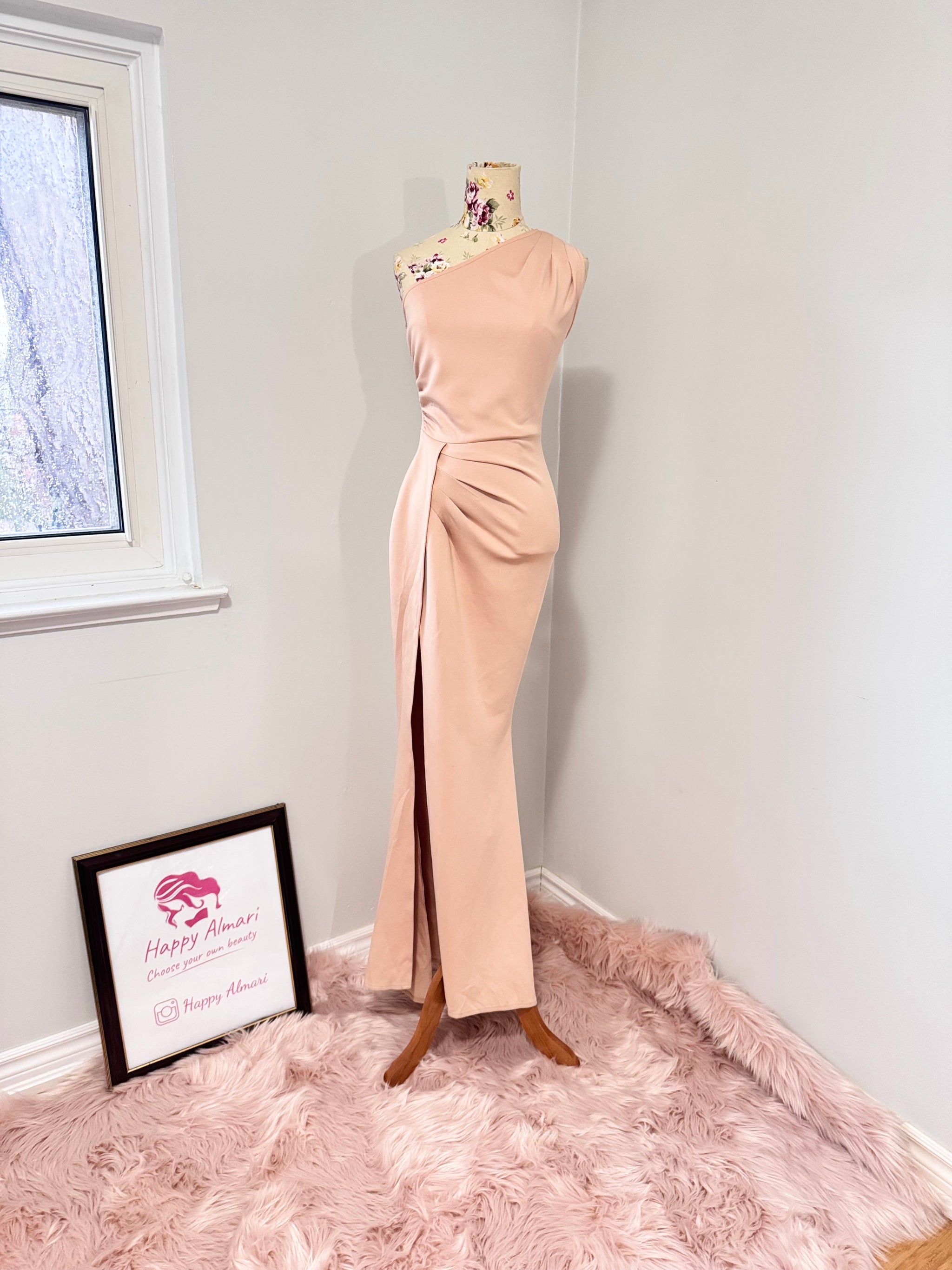Make an unforgettable entrance in this stunning one-shoulder gown, designed to accentuate your curves with effortless grace. Featuring a sleek asymmetrical neckline and elegantly draped side ruching, this dress flatters from every angle. The high-slit detail adds just the right touch of allure, making it the perfect choice for weddings, formal events, or any special occasion where you want to shine. The soft blush hue complements a variety of skin tones, ensuring a timeless and sophisticated look. 