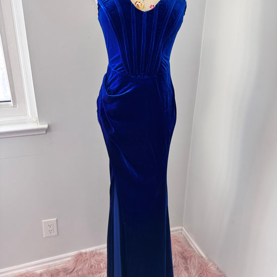 Step into timeless elegance with this breathtaking previously cherished royal blue velvet evening gown, designed to turn heads at any event. Crafted from rich, ultra-soft velvet, this figure-hugging masterpiece features a structured corset bodice with delicate pleated detailing that accentuates your silhouette. The sweetheart neckline adds a touch of romance, while the flowing skirt with a sultry thigh-high slit creates the perfect balance of sophistication and allure. In perfect condition.