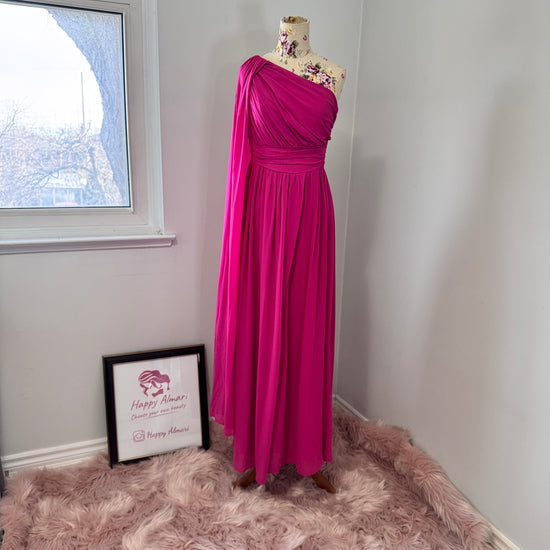 Step into effortless elegance with this breathtaking fuchsia one-shoulder gown, designed to make a statement at any event. Featuring a gracefully draped sleeve that cascades like a flowing waterfall, this dress exudes confidence, sophistication, and timeless charm. The cinched waist enhances your silhouette, while the soft, flowing fabric moves beautifully with every step.