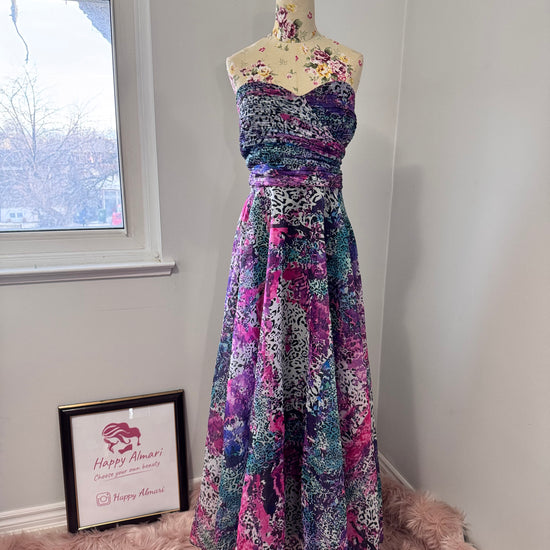 Unleash your bold, vibrant spirit with this breathtaking strapless gown, a mesmerizing fusion of art and fashion. Designed to turn heads, this flowing masterpiece features an explosion of rich purples, electric blues, and striking pinks in a captivating abstract animal print. The ruched bodice flatters the silhouette, while the voluminous skirt cascades effortlessly, creating a dreamy, ethereal effect with every step. 