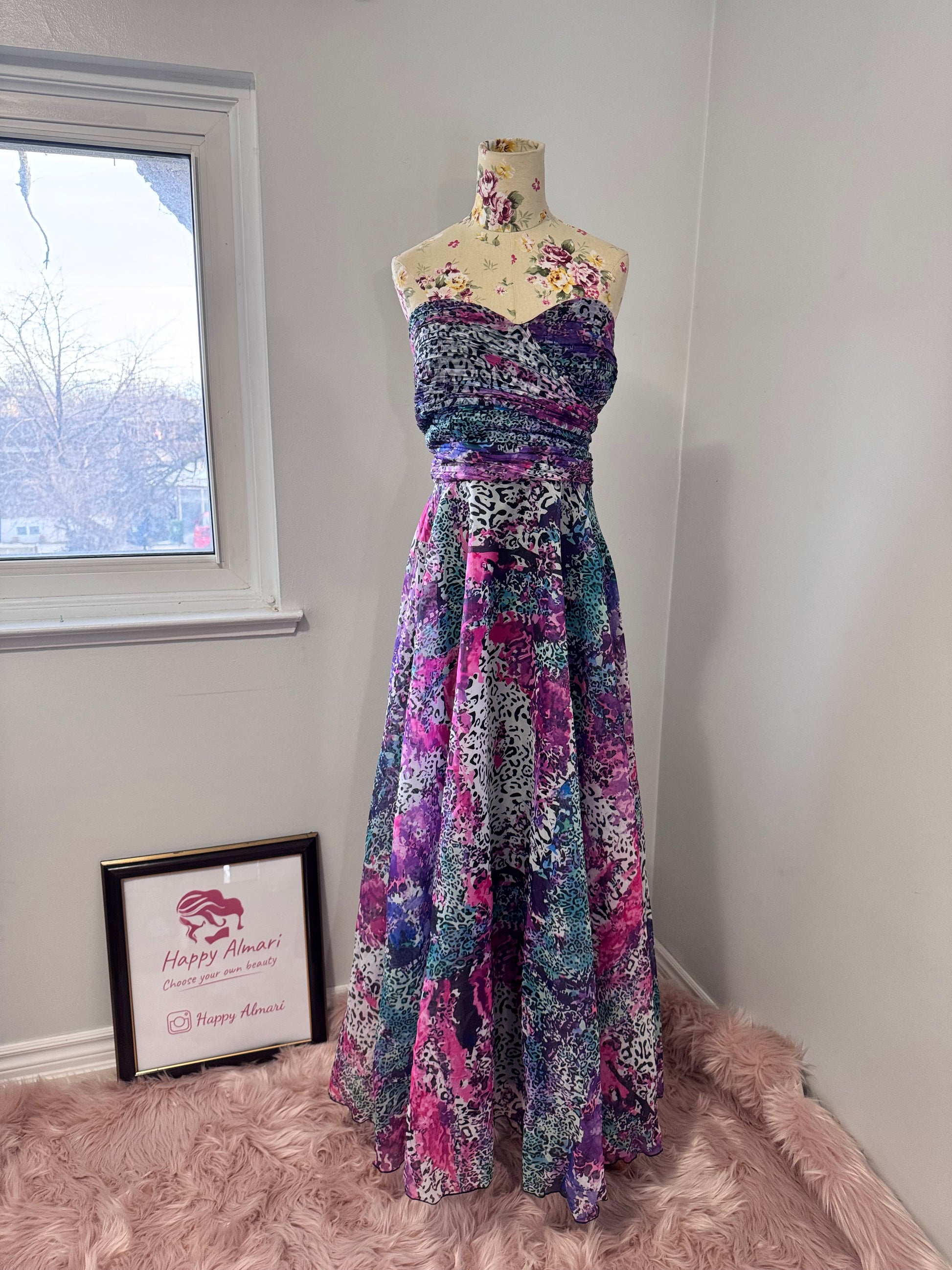 Unleash your bold, vibrant spirit with this breathtaking strapless gown, a mesmerizing fusion of art and fashion. Designed to turn heads, this flowing masterpiece features an explosion of rich purples, electric blues, and striking pinks in a captivating abstract animal print. The ruched bodice flatters the silhouette, while the voluminous skirt cascades effortlessly, creating a dreamy, ethereal effect with every step. 