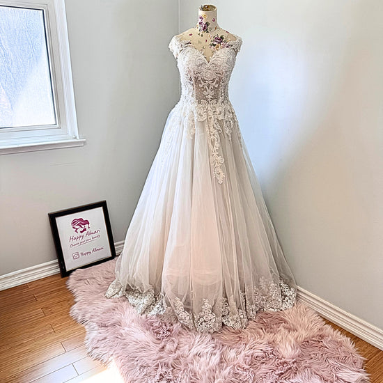 Ethereal elegance meets timeless romance in this breathtaking bridal gown, designed to make you feel like an absolute vision on your special day. Featuring an intricately beaded bodice with delicate lace appliqués cascading onto a flowing tulle skirt, this gown embodies grace and sophistication. The illusion off-shoulder neckline and sweetheart design create a captivating silhouette, while the soft, airy layers add a dreamy, fairytale-like effect with every step. 