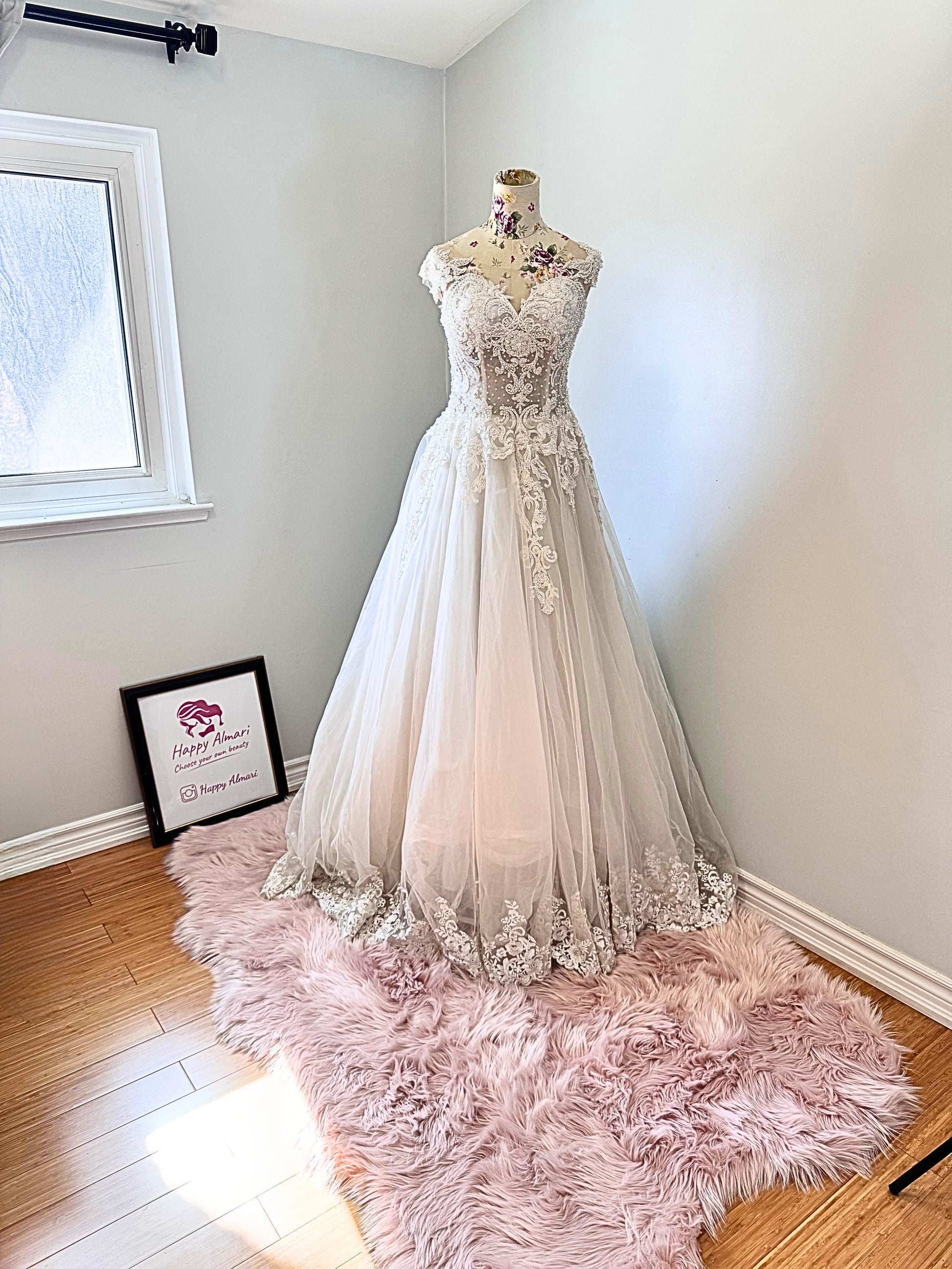 Ethereal elegance meets timeless romance in this breathtaking bridal gown, designed to make you feel like an absolute vision on your special day. Featuring an intricately beaded bodice with delicate lace appliqués cascading onto a flowing tulle skirt, this gown embodies grace and sophistication. The illusion off-shoulder neckline and sweetheart design create a captivating silhouette, while the soft, airy layers add a dreamy, fairytale-like effect with every step. 