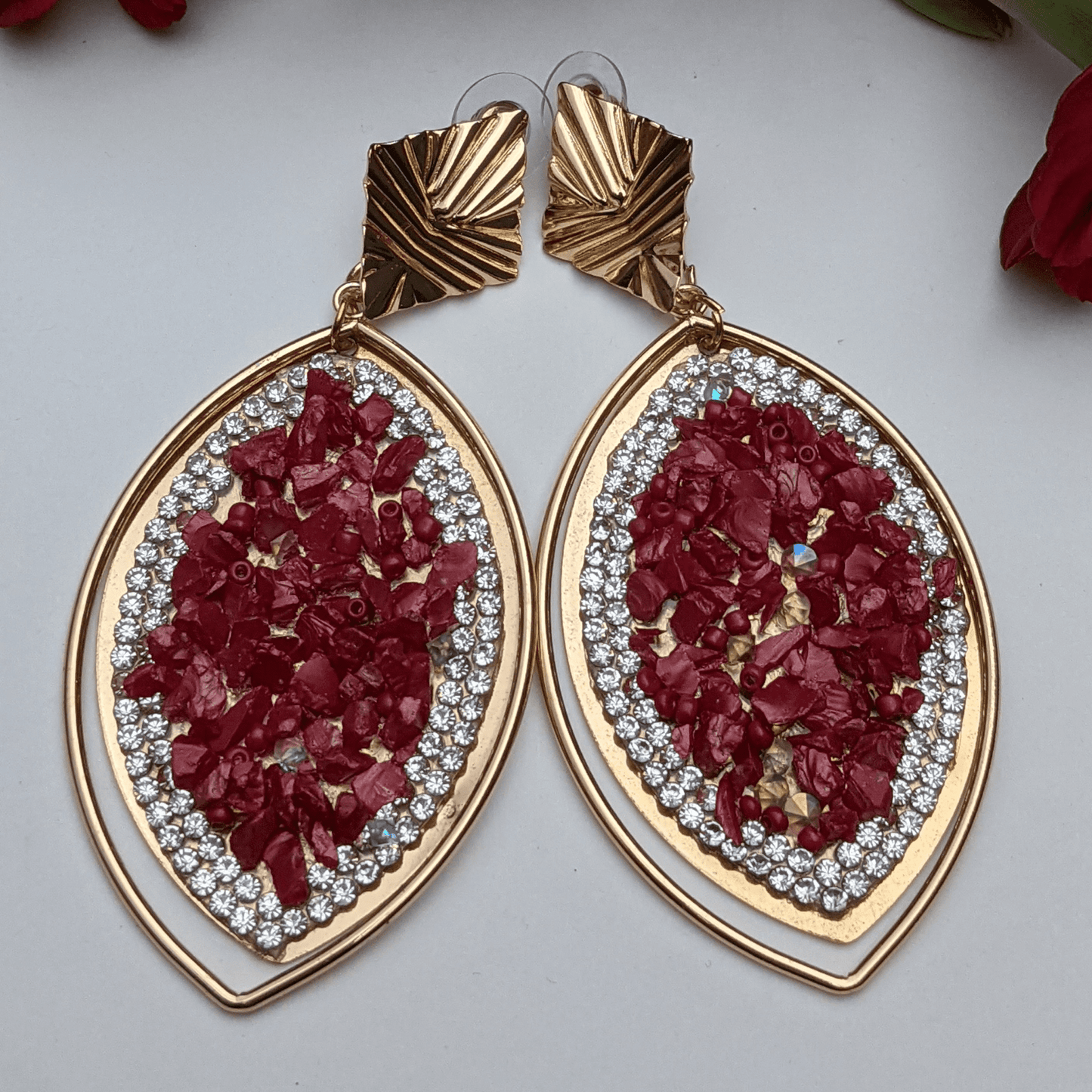 A perfect blend of luxury and elegance! These eye-catching earrings feature a stunning marquise-shaped design, adorned with&nbsp;crimson-red gemstone chips, dazzling rhinestones, and a sleek gold-tone frame that exudes sophistication. The unique geometric gold accents add a modern touch, making them the perfect accessory for fashion-forward women who love to stand out. Whether you're dressing up for a glamorous evening, a festive celebration, or adding a bold touch to your everyday look.