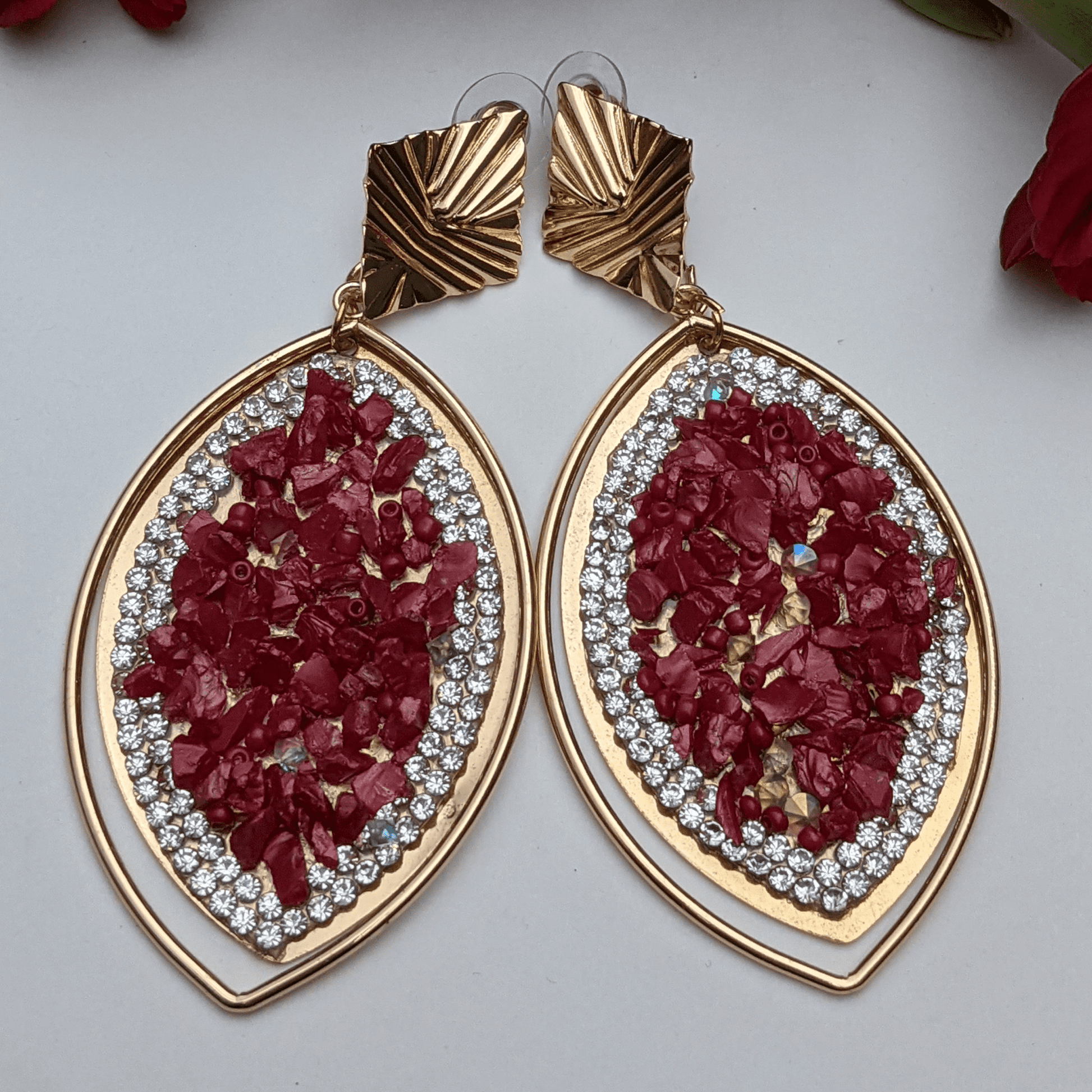 A perfect blend of luxury and elegance! These eye-catching earrings feature a stunning marquise-shaped design, adorned with&nbsp;crimson-red gemstone chips, dazzling rhinestones, and a sleek gold-tone frame that exudes sophistication. The unique geometric gold accents add a modern touch, making them the perfect accessory for fashion-forward women who love to stand out. Whether you're dressing up for a glamorous evening, a festive celebration, or adding a bold touch to your everyday look.