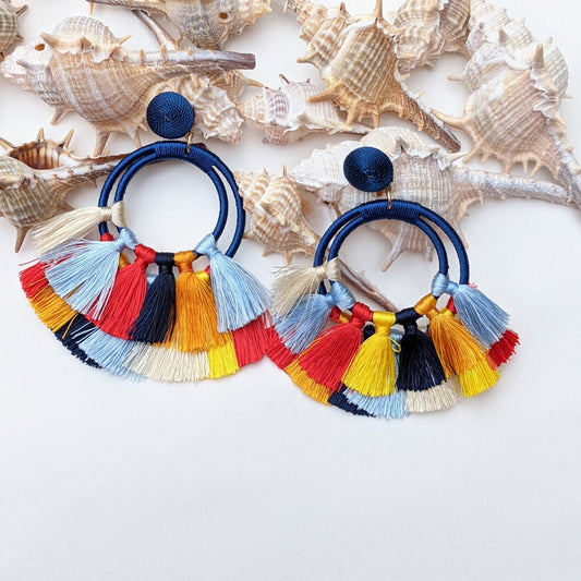 Add a bold pop of color to your look with these tassel earrings, featuring vibrant colours that sway with every move. Lightweight yet eye-catching and made with premium thread, wrapped hoops, and chic fabric-covered studs, they blend comfort with standout style. 