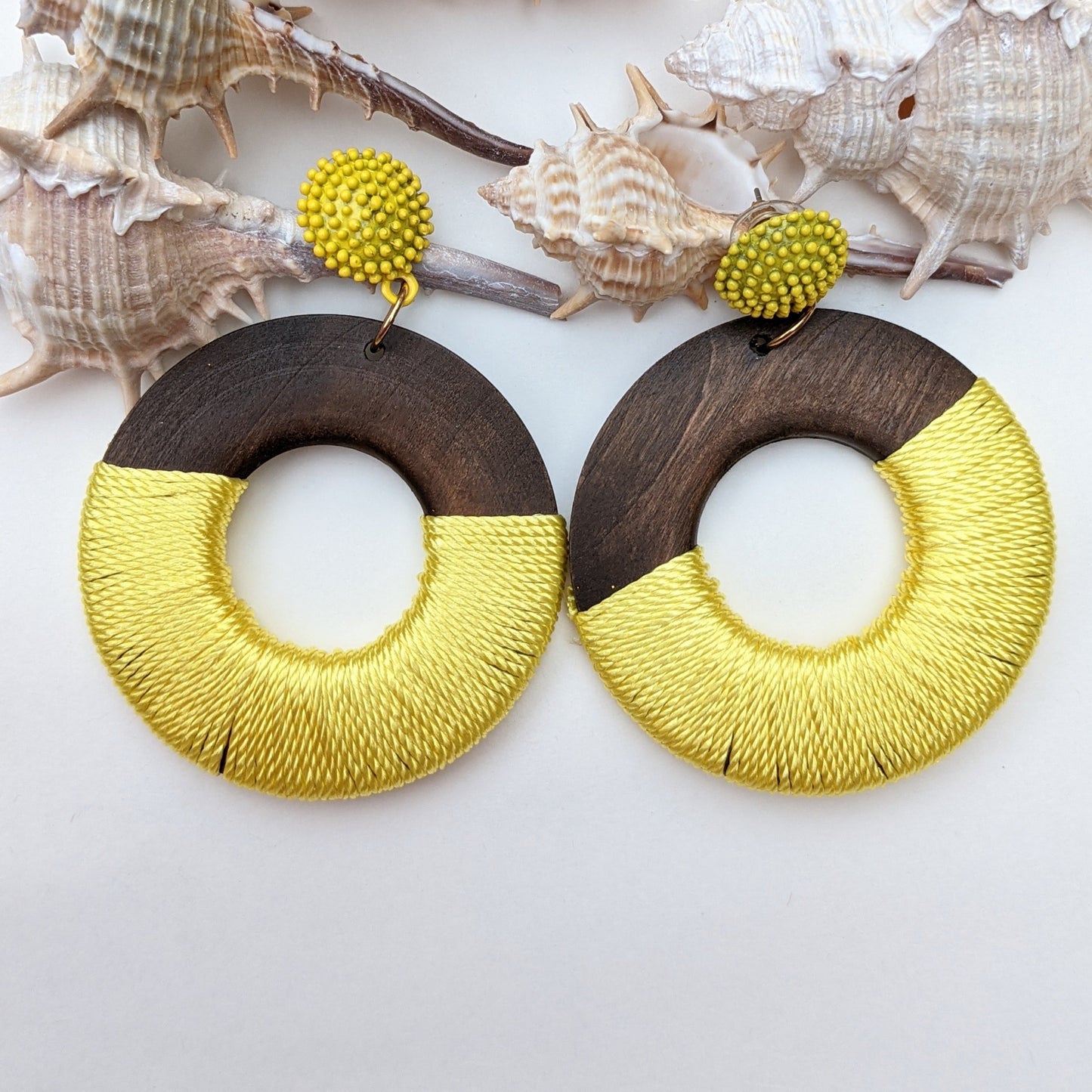 A perfect fusion of natural elegance and vibrant charm! These statement earrings feature dark polished wooden hoops partially wrapped in a bold, sunshine-yellow thread, creating an eye-catching contrast that embodies both earthy warmth and contemporary style. Designed for the modern trendsetter, they are lightweight, stylish, and effortlessly elevate any outfit.