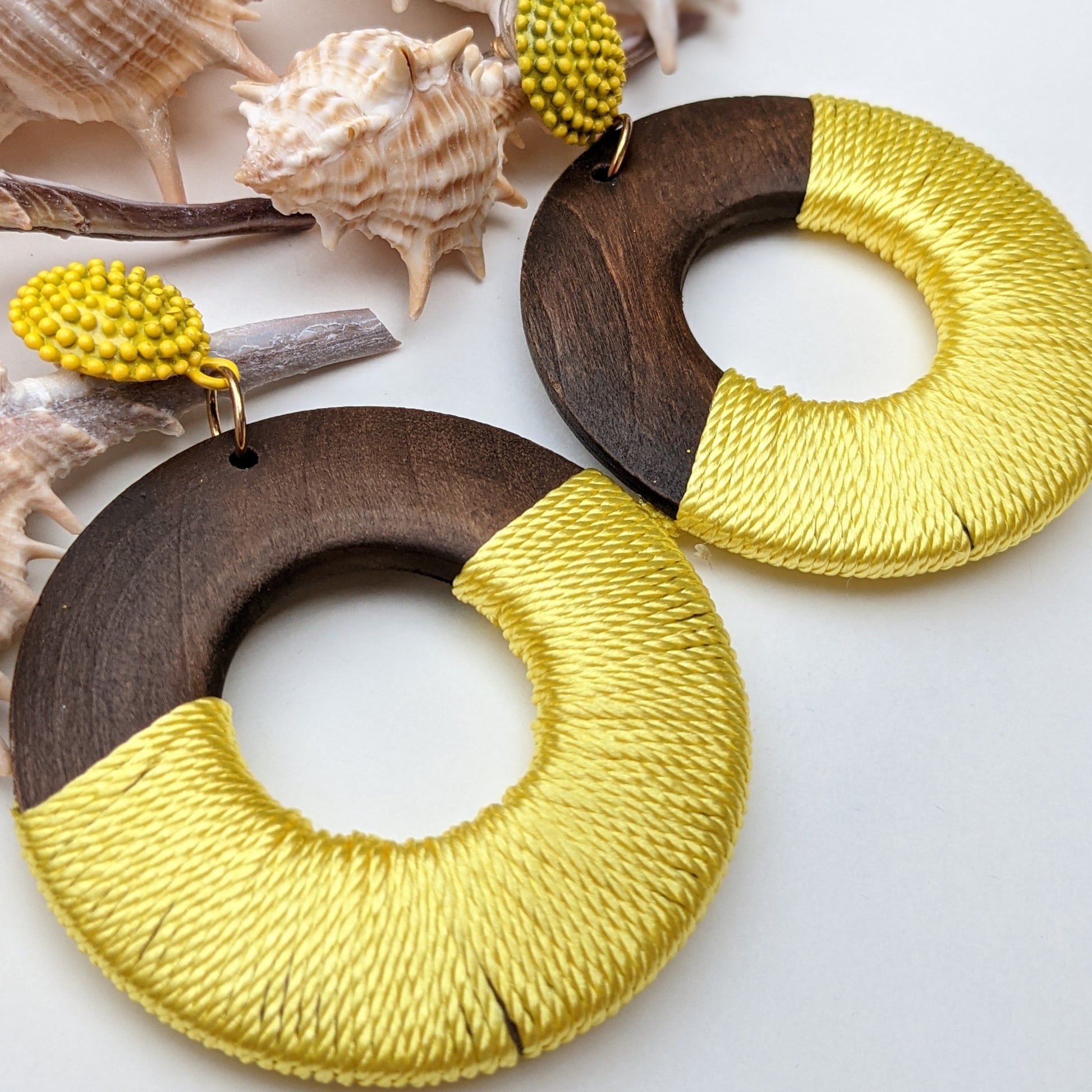 A perfect fusion of natural elegance and vibrant charm! These statement earrings feature dark polished wooden hoops partially wrapped in a bold, sunshine-yellow thread, creating an eye-catching contrast that embodies both earthy warmth and contemporary style. Designed for the modern trendsetter, they are lightweight, stylish, and effortlessly elevate any outfit.