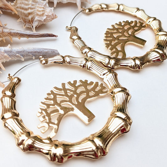 Elevate your style with these stunning&nbsp;gold bamboo hoop earrings, featuring an intricate Tree of Life centerpiece—a timeless symbol of strength, growth, and connection. Crafted with exquisite detail, these bold statement earrings boast a radiant high-polish gold finish, capturing the essence of nature’s beauty while exuding luxury and sophistication. These hoops are the perfect blend of earthy elegance and contemporary fashion, making them a must-have for your collection.